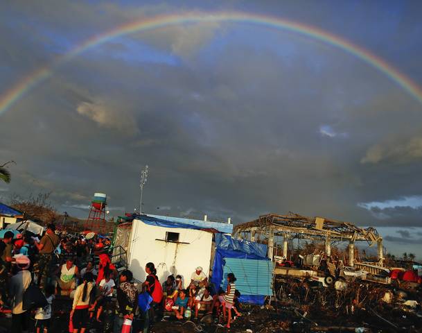 A rainbow appears above Typhoon Haiyan survivors desperate to catch a flight from the Tacloban airport